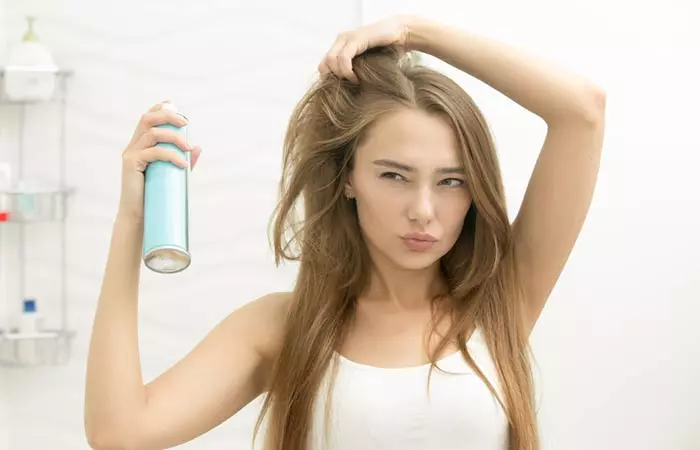 Woman using hairspray on baby hair