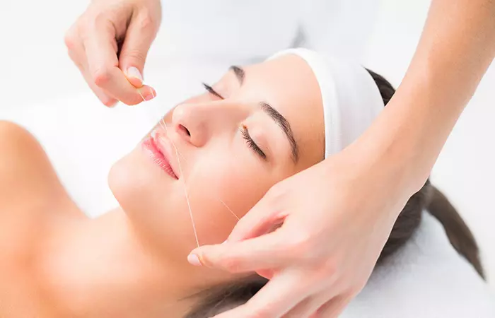 Threading to remove white facial hair A beautician doing threading to remove facial hair