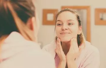 Woman massaging argan oil on her face
