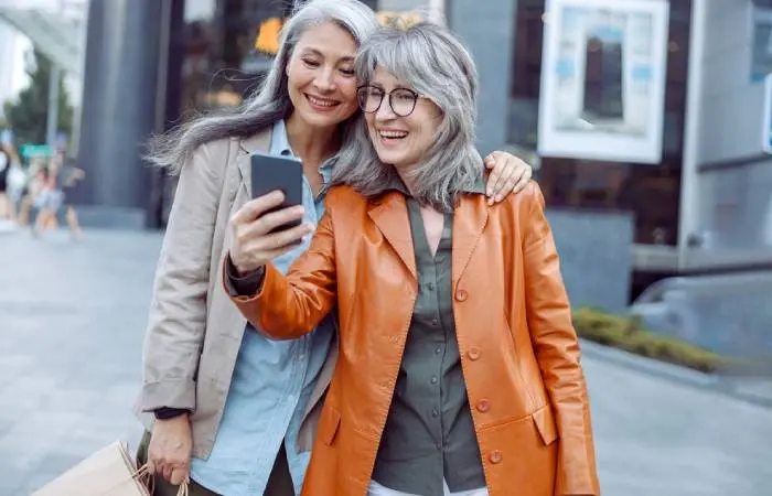 Two women with gray hair and stylish clothes taking a selfie