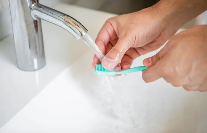 A person cleaning toothbrush