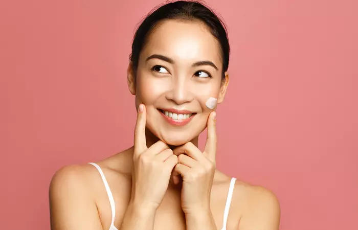 Woman applying allantonin-infused moisturizer to hydrate skin