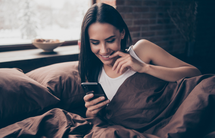  Woman reading a good morning text in bed
