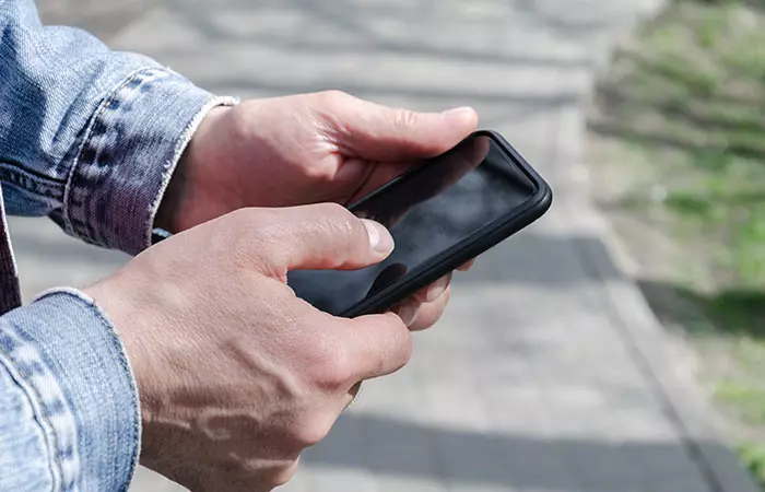 Using Both Hands To Hold Phone And One Thumb To Scroll And Type