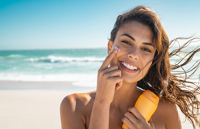 Woman applying sunscreen to prevent and treat sallow skin