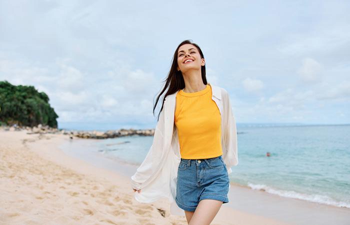 Leo woman wearing a tank top, a casual shrug, and denim shorts.
