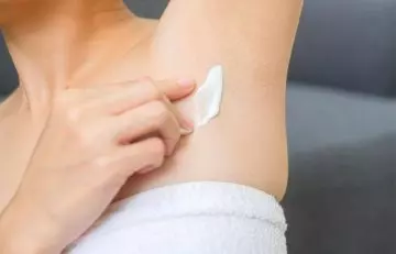 Woman applying topical ointment to relieve armpit rash.