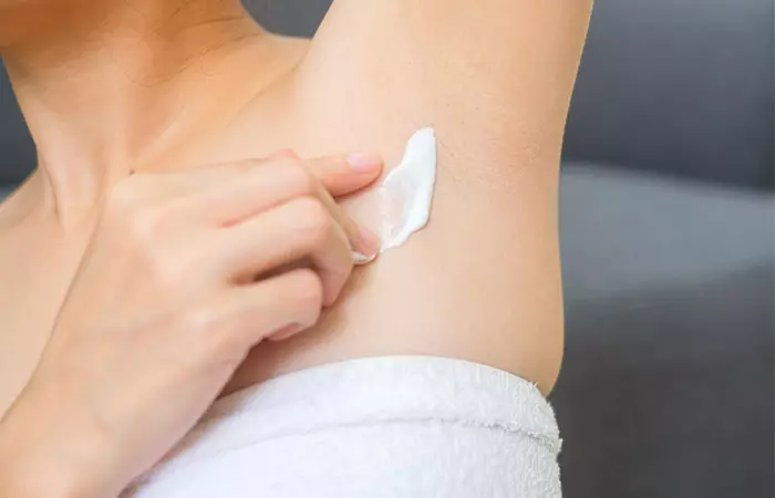 Woman applying topical ointment to relieve armpit rash.