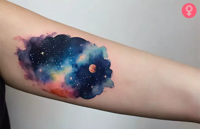 A woman with a watercolor space tattoo on her forearm