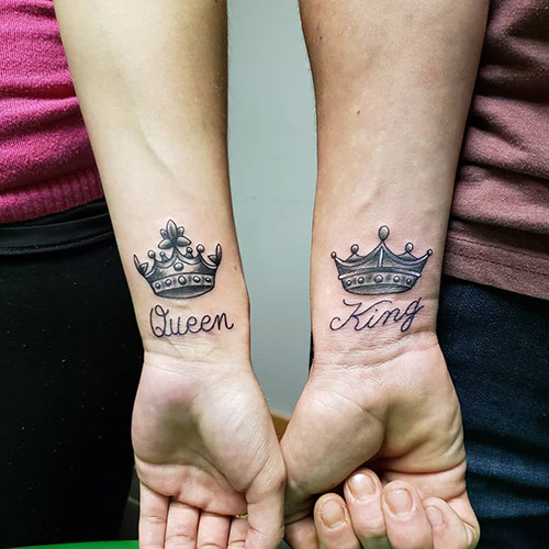 The words king and queen along with the crowns tattoo on wrists
