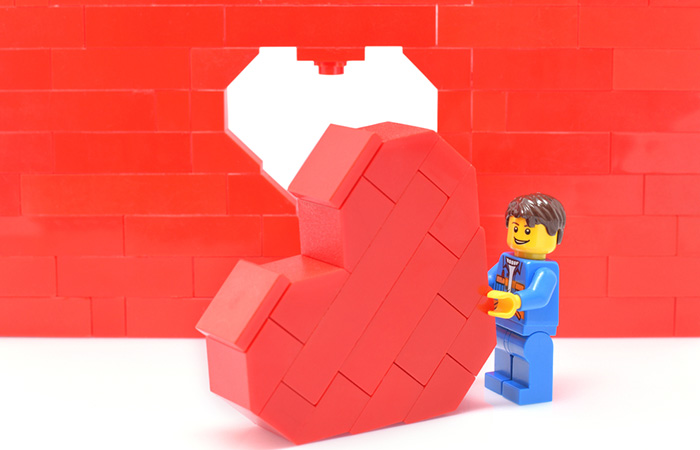 Lego figure building a red Lego heart