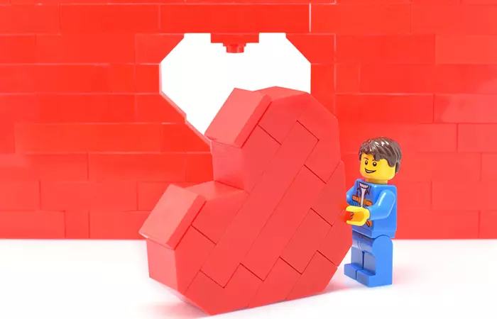Lego figure building a red Lego heart