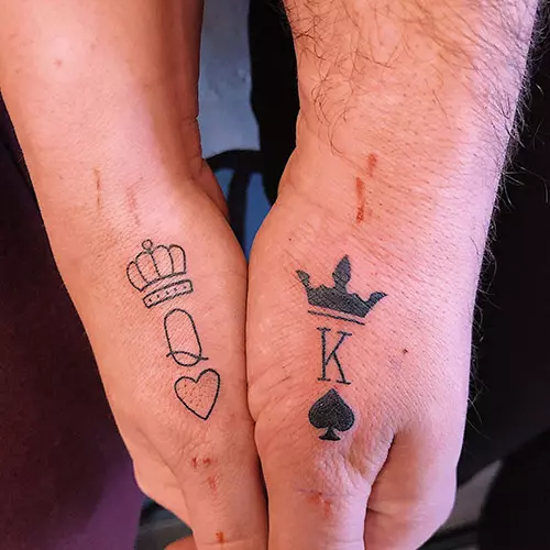 King and queen tattoos on thumbs with the letters q and k along with crowns and a heart and spade