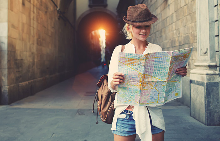 Young woman checking directions on the map while traveling