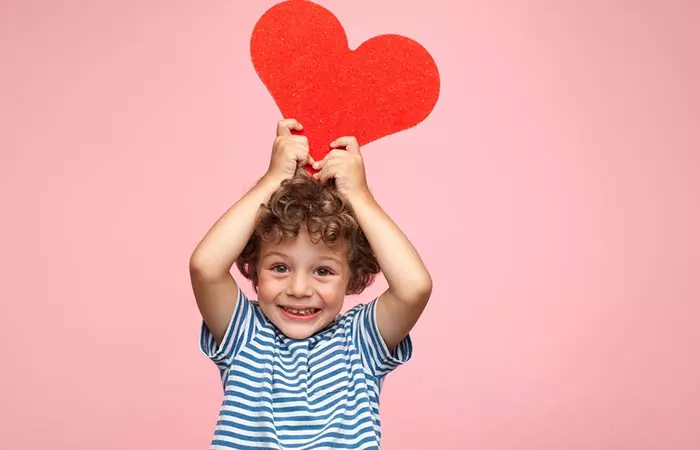 a happy kid holding heart-shaped paper