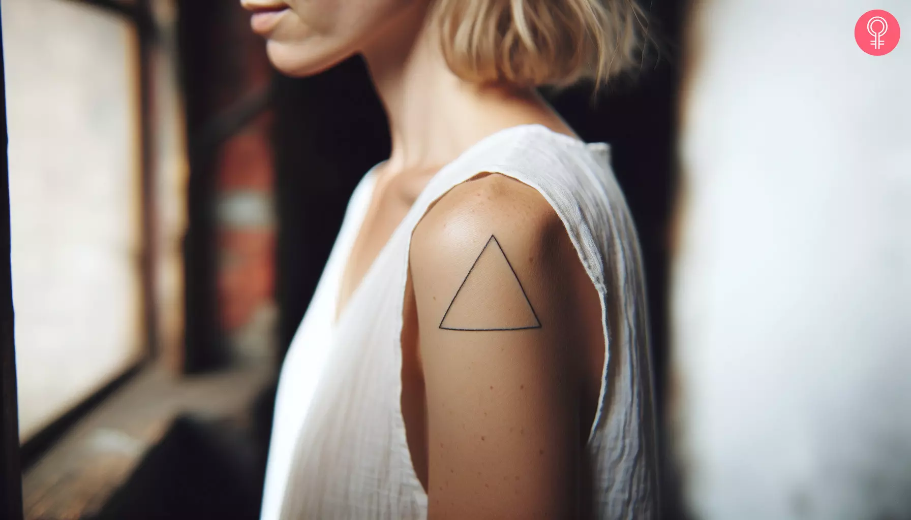 A woman with a fine line triangle tattoo on her upper arm