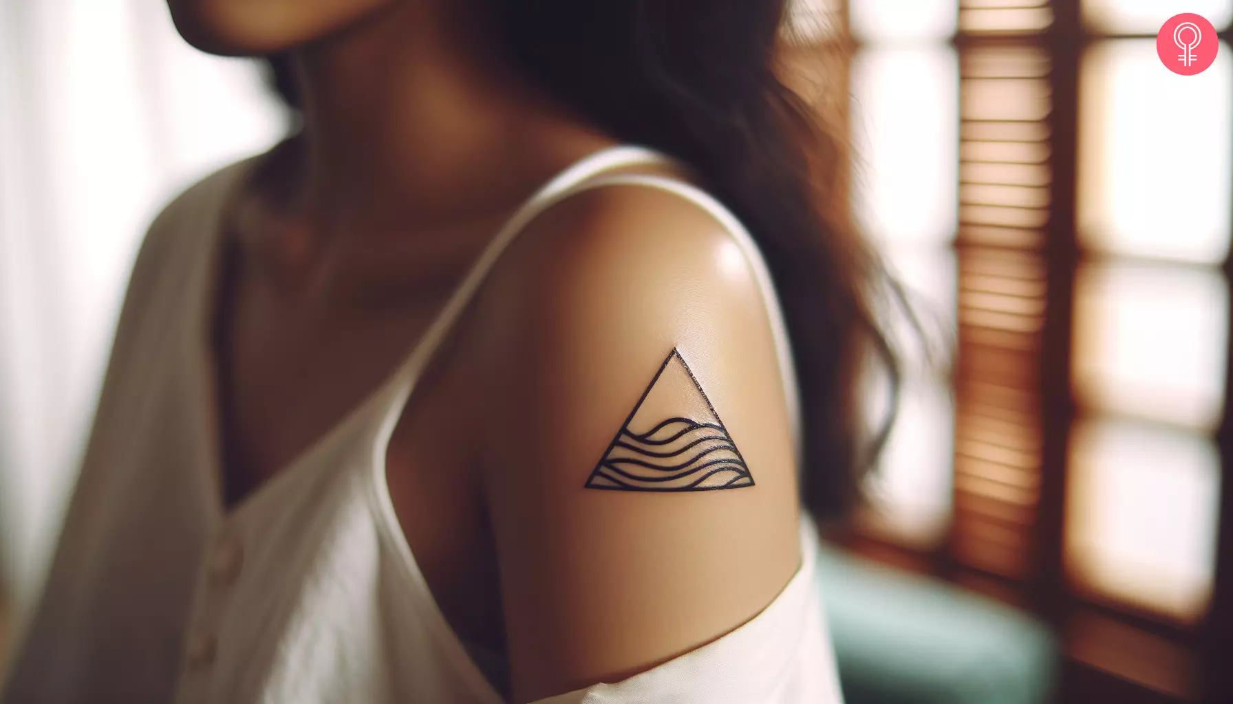A woman with a minimalist triangle wave tattoo on her upper arm