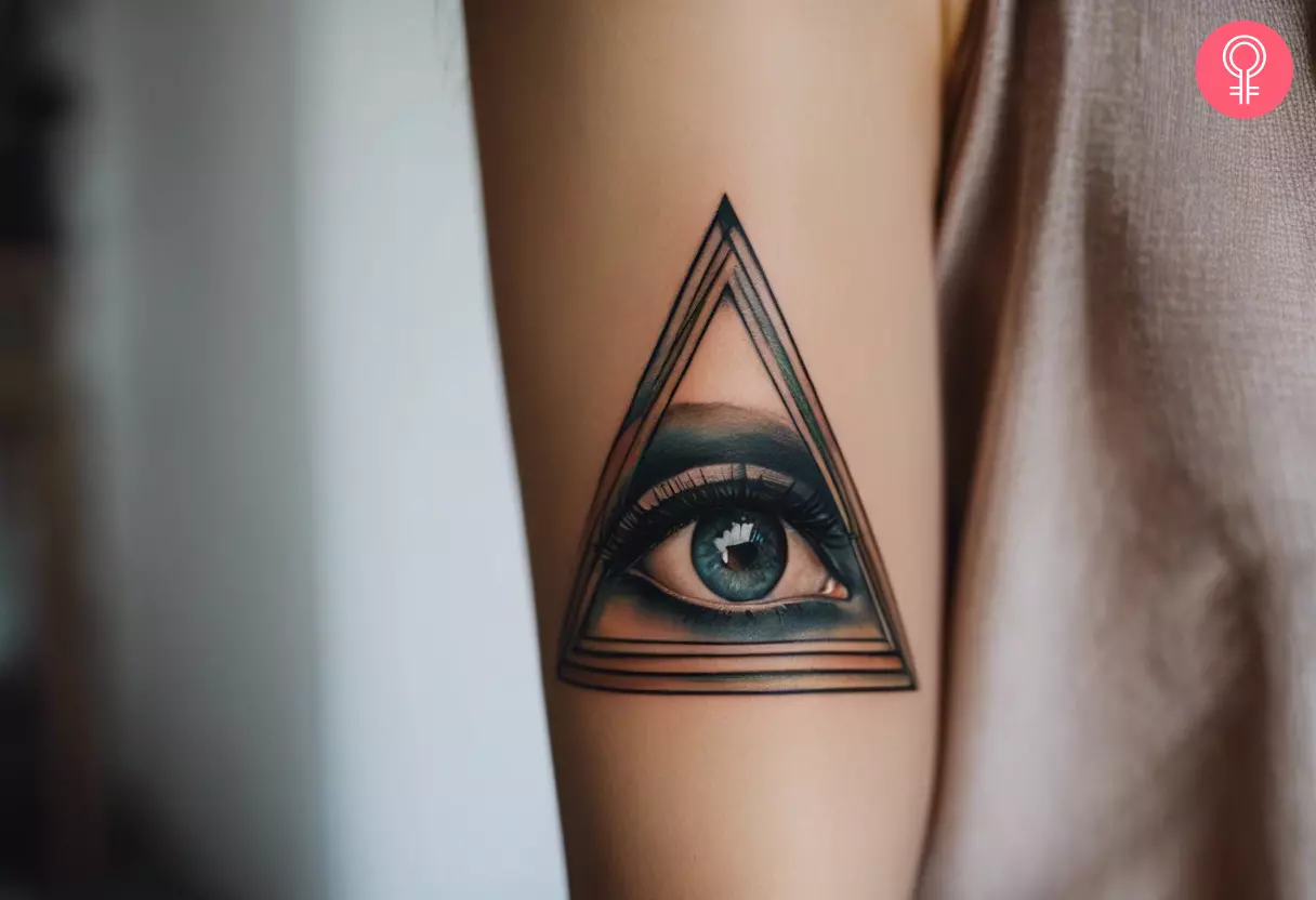 A woman with a realistic triangle eye tattoo on her forearm