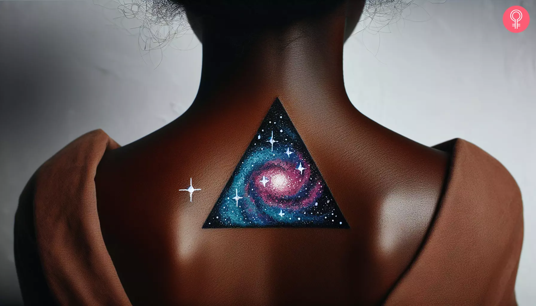 A woman with a vibrant triangle galaxy tattoo on her upper back