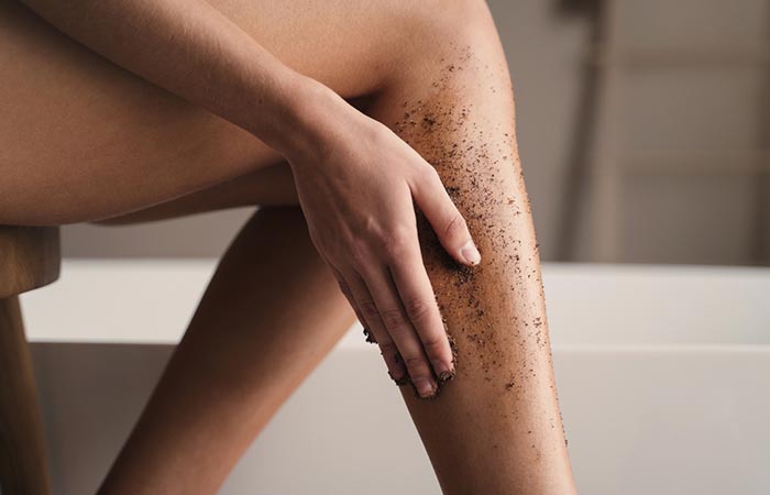 Woman exfoliating her legs to lighten the appearance of stretch marks