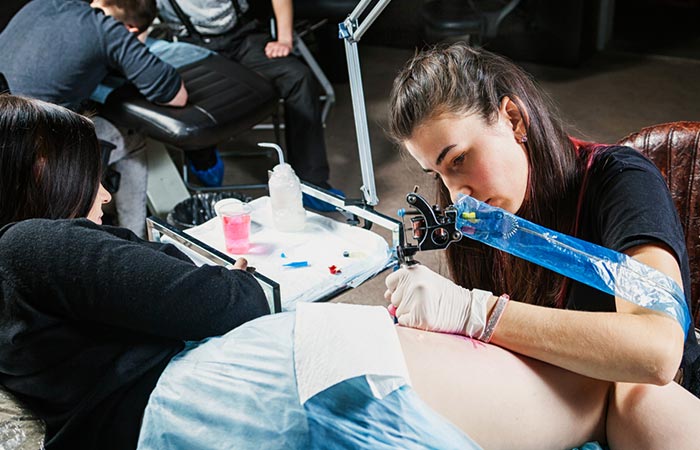 Woman getting tattoo on her thigh to cover strech marks.