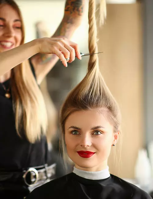 A hairdresser cutting hair after making a front ponytail