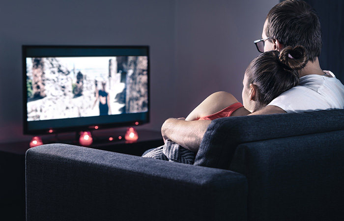 Cozy couple watching romantic movie on TV