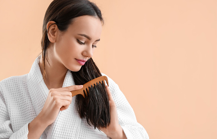 Woman combing hair with coconut oil as a leave-in conditioner