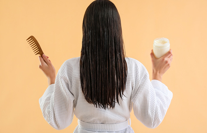 Woman with a comb and coconut oil jar before shampooing