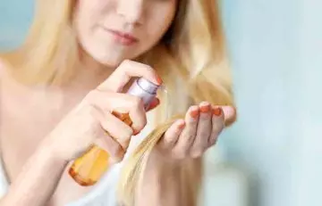 Woman applying deep-penetrating hair oil to take care of her bleached hair