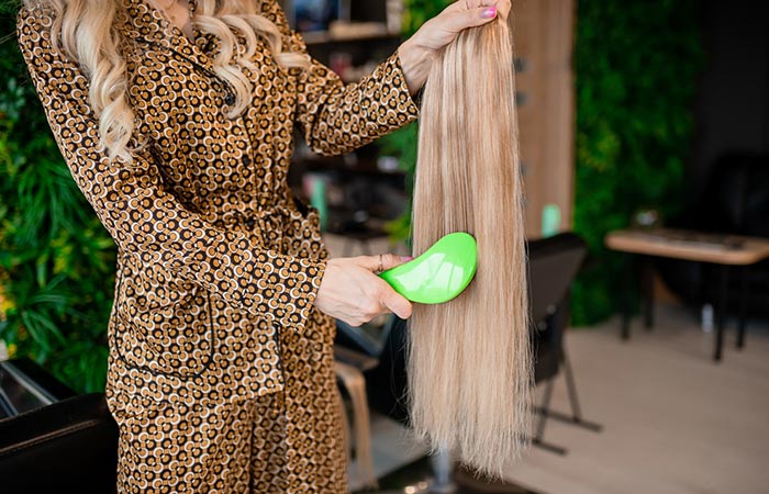 Woman detangling hair extensions with a brush