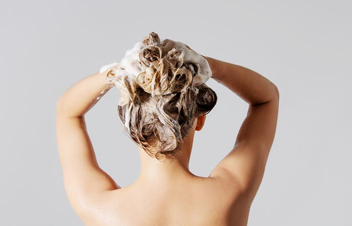 Woman washing her hair to remove castor oil. 