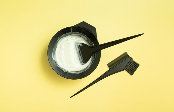 A bowl of bleach and applicator brushe and comb