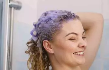 Woman using purple shampoo to take care of her bleached hair