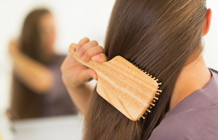 Woman brushing hair smoothly after applying mineral oil