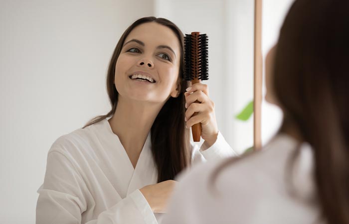 Woman combing hair with natural bristle brush
