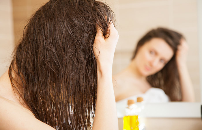 Woman applying mineral oil on hair to tame tresses