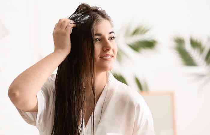 Woman applying hair mask infused with coconut oil to treat dry scalp