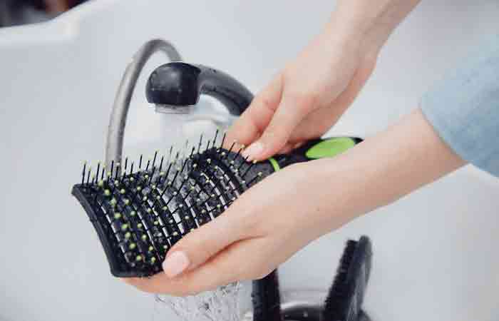 Person washing hair brush under the tap