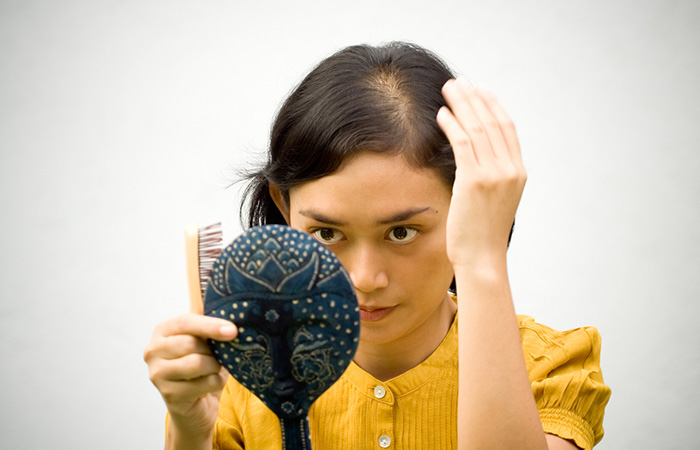 Woman combing her hair before applying emu oil