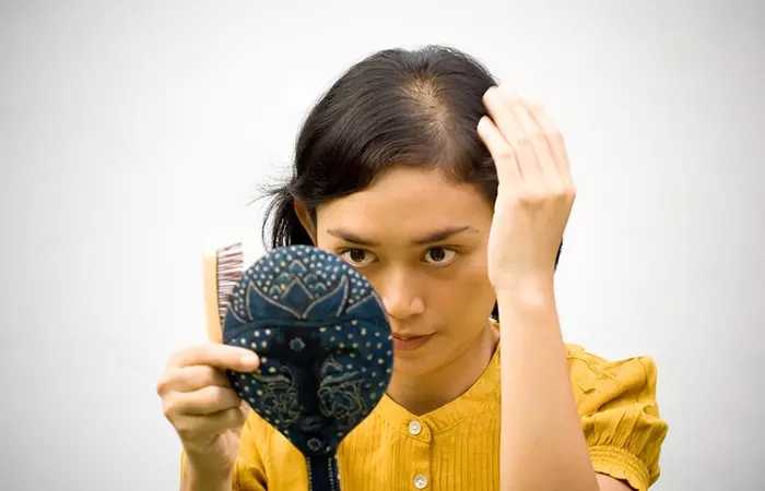 Woman combing her hair before applying emu oil