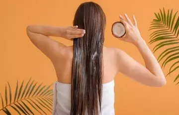 A girl applying coconut oil on her hair