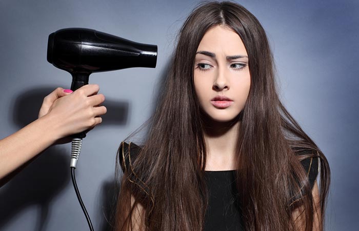Woman drying damp hair with hair dryer