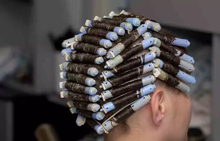 Woman with perming rolls in a salon