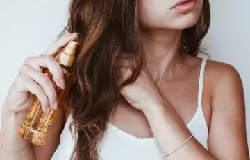 Woman spraying mineral oil on her hair