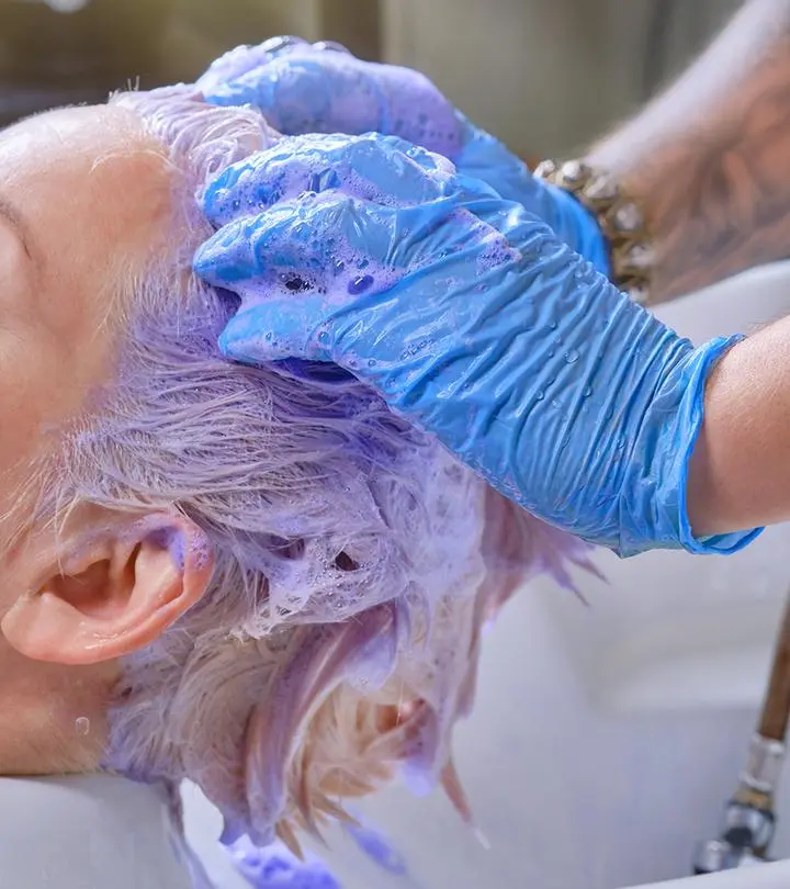 A woman getting her hair shampooed with purple shampoo