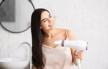 Woman blow drying hair on cool setting