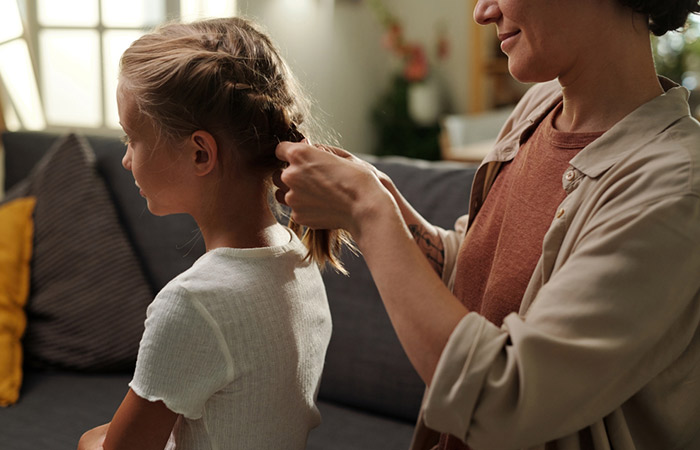Close-up of a mother braiding her daughter's hair.