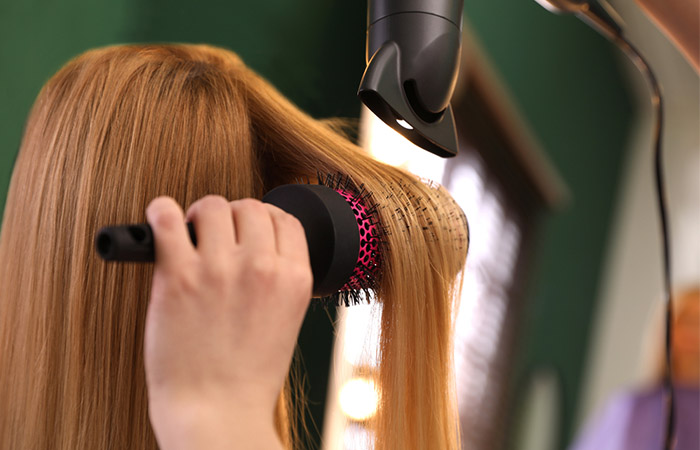 Close-up of a hairstylist blow-drying and brushing a woman's hair in a salon