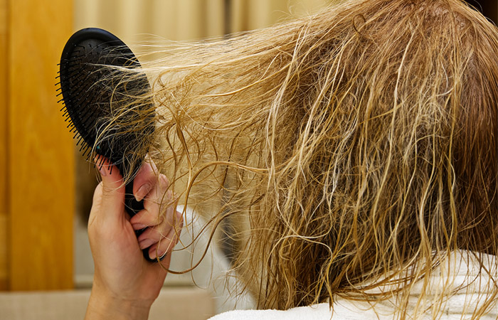 Woman brushing damaged and frizzy hair